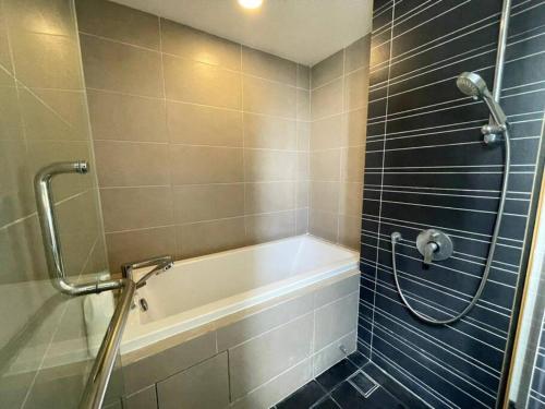 a bathroom with a bath tub and a shower at Teega Suites Seaview by VDO Homestay in Nusajaya
