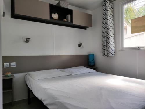 une chambre avec un lit blanc avec une fenêtre dans l'établissement Mobil-Home 2 chambres camping 4 étoiles, à Fréjus