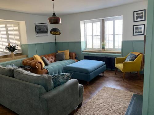 a living room with a couch and a blue ottoman at Luxurious & modern on-the-beach family retreat in Boulmer