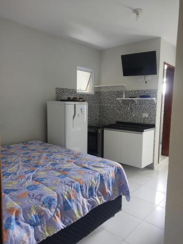 a bedroom with a bed and a refrigerator and a tv at Kitnets & Flats in Ubatuba