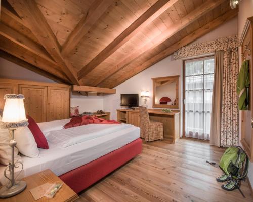 a bedroom with a large bed in a room with wooden ceilings at Bio Hotel Hermitage in Madonna di Campiglio