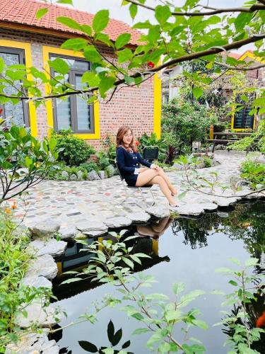 a woman sitting on a stone bridge over a pond at Ninh Binh Royal Homestay in Ninh Binh