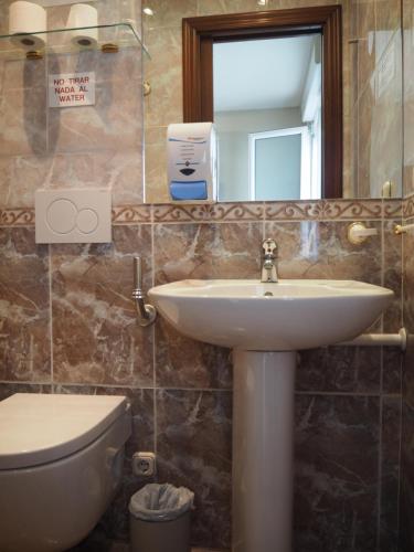 a bathroom with a sink and a toilet and a mirror at Hostal Acella in Pamplona