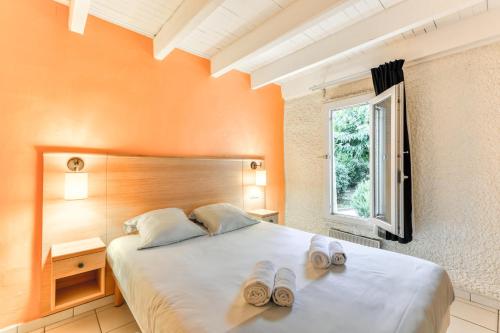 una camera da letto con un letto e due pantofole sopra di SOWELL RESIDENCES Les Lauriers Roses a Cap d'Agde