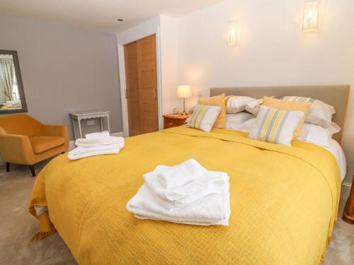a bedroom with a large yellow bed with towels on it at Bryants Cottage in Chulmleigh