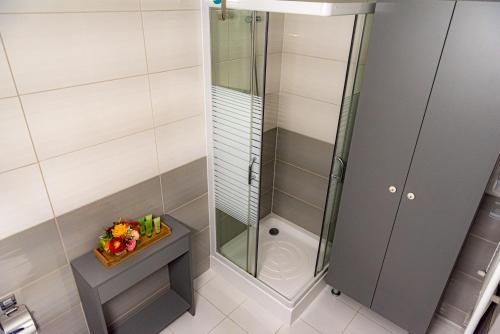 La salle de bains est pourvue d'une douche avec une porte en verre. dans l'établissement Pastel Apartments, à Braşov