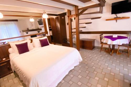 a bedroom with a large white bed and a table at Pousada O Cantinho da Raposa in Monte Verde