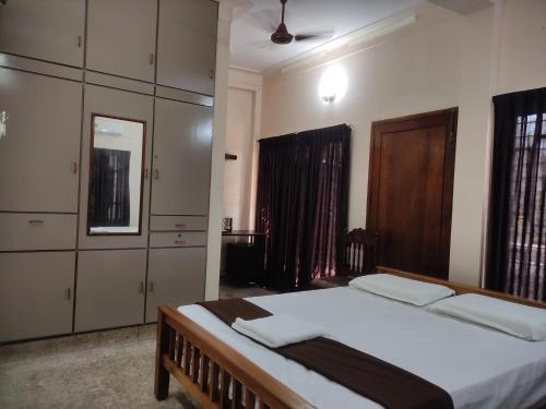 a bedroom with a bed and cabinets and a mirror at Sreevalsam Guest House in Trivandrum