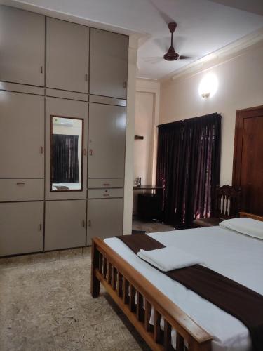 a bedroom with a large bed and cabinets and a window at Sreevalsam Guest House in Trivandrum
