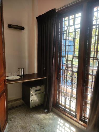 a room with a window with a table and a windowtaining at Sreevalsam Guest House in Trivandrum
