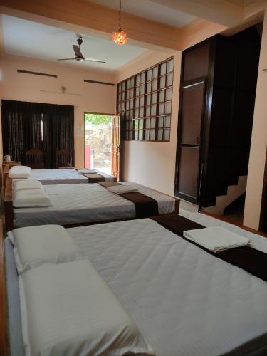 a row of beds lined up in a room at Sreevalsam Guest House in Trivandrum