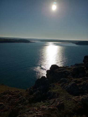 a view of the ocean with the sun shining on the water at Sharlands Farm Bed and Breakfast in Bude