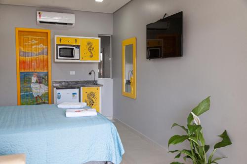 a room with a bed and a kitchen with yellow cabinets at Pousada Guaricana in Pontal do Paraná