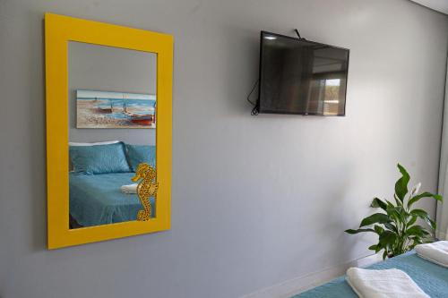 a mirror with a yellow frame on a wall at Pousada Guaricana in Pontal do Paraná