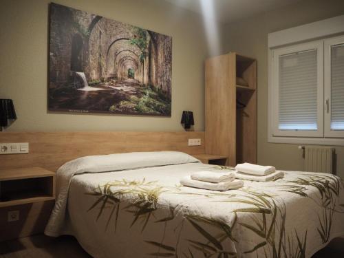 a bedroom with a bed with a painting on the wall at Hostal Acella in Pamplona