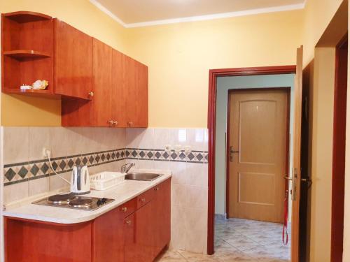 a kitchen with wooden cabinets and a sink and a door at BetaNovalja in Novalja