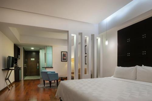 a bedroom with a large bed and a chair at Holiday Inn Santo Domingo by IHG in Santo Domingo