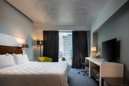 a hotel room with a bed and a desk and a window at Holiday Inn Santo Domingo by IHG in Santo Domingo