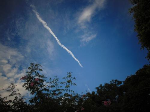 a jet trail in the sky above some trees at Rancho do Colega in Santa Branca