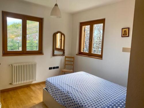 1 dormitorio con 1 cama azul y 2 ventanas en Cavedago / Andalo con giardino, en Cavedago