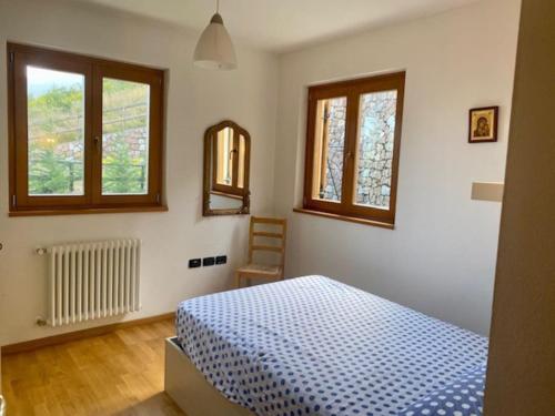 a bedroom with a blue bed and two windows at Cavedago / Andalo con giardino in Cavedago