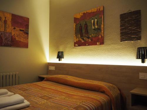 a bedroom with a bed and two pictures on the wall at Hostal Acella in Pamplona