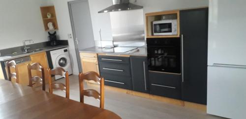a kitchen with a table and chairs and a microwave at GITE DE LA POILANE in Saint-Aubin-de-Luigné