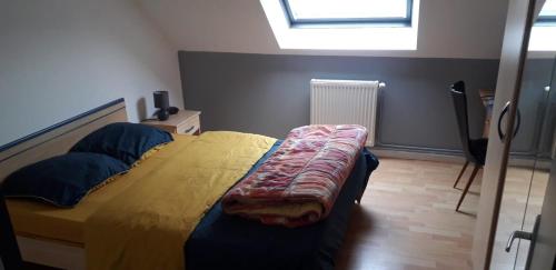 a bedroom with a bed with a yellow comforter and a window at GITE DE LA POILANE in Saint-Aubin-de-Luigné