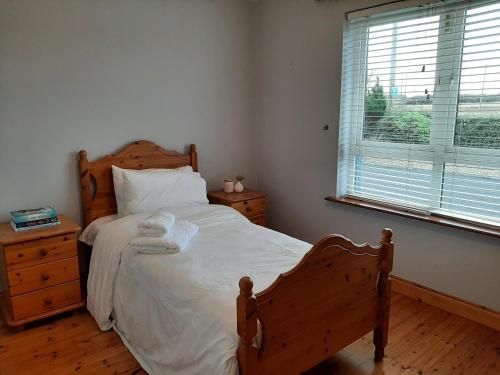 a bedroom with a bed and a dresser and a window at Skye's Atlantic Retreat in Milltown Malbay