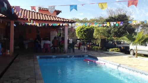 a swimming pool in a yard with people standing around it at Rancho do Colega in Santa Branca