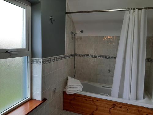 a bathroom with a tub and a shower with a shower curtain at Skye's Atlantic Retreat in Milltown Malbay