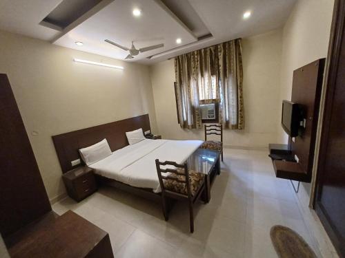 een slaapkamer met een bed en een televisie. bij Hotel Raghav Palace in Jaipur