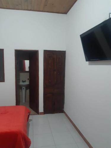ein Wohnzimmer mit einem TV und einer roten Couch in der Unterkunft Hotel Lili Popayán - Sede 2 in Popayan