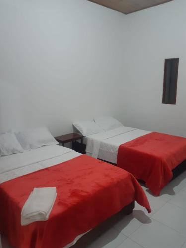 two beds with red sheets in a room at Hotel Lili Popayán - Sede 2 in Popayan