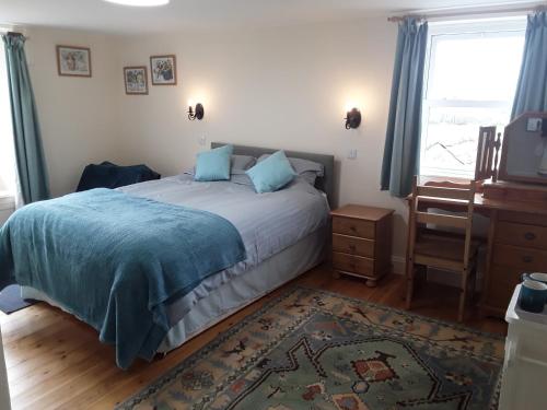 a bedroom with a bed with a blue blanket and a window at Sharlands Farm Bed and Breakfast in Bude