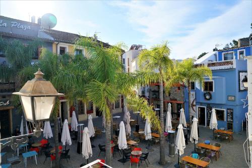 une rue avec des tables, des parasols et des palmiers dans l'établissement Romantico Apartamento en el Puerto de Denia, à Dénia