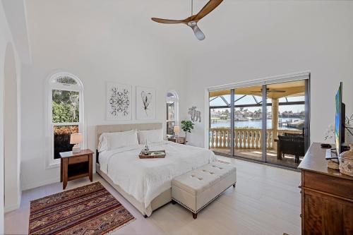 Un dormitorio blanco con una cama y un balcón. en Serene waterfront home with pool, spa, and water view, en Marco Island
