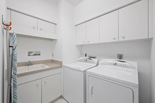 lavadero blanco con armarios blancos y lavadora y secadora en Serene waterfront home with pool, spa, and water view, en Marco Island