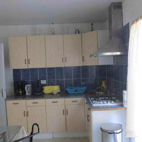 une cuisine avec des placards blancs et du carrelage bleu sur le mur. dans l'établissement maison rez de chaussée 3 chambres, à Bompas