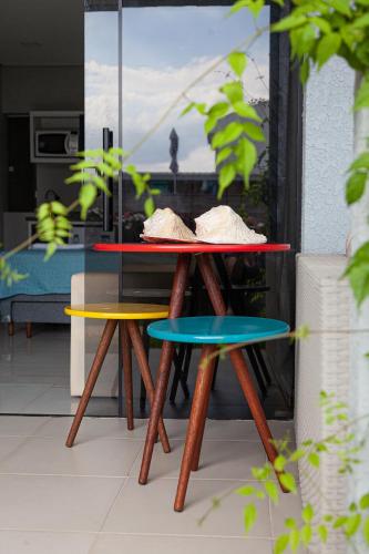 a table and two stools in front of a window at Pousada Guaricana in Pontal do Paraná