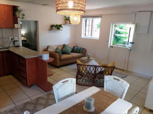 uma cozinha e uma sala de estar com mesa e cadeiras em Santika Getaway Cottage Stellenbosch em Stellenbosch