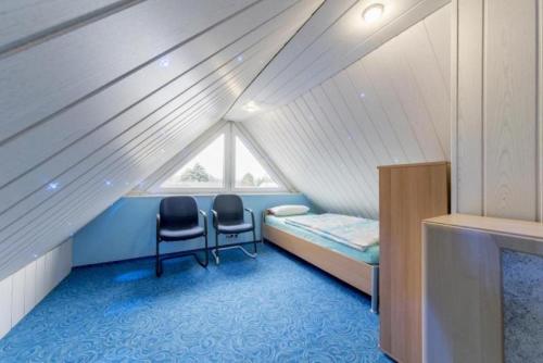 a room with two chairs and a bed in a attic at Private House in Hannover