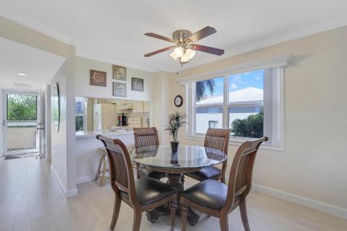 a dining room with a table and chairs and a ceiling fan at Bright condo in community with pool/steps to beach in Marco Island