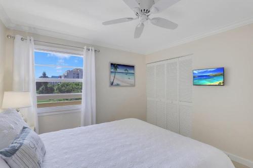 a white bedroom with a bed and a window at Bright condo in community with pool/steps to beach in Marco Island