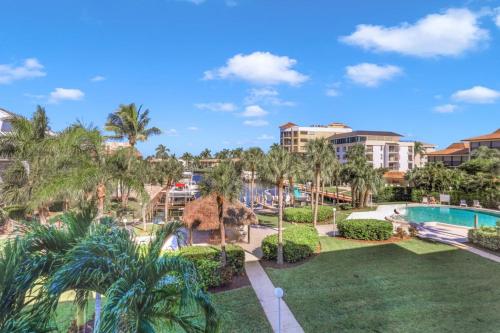 a resort with a pool and palm trees at Bright condo in community with pool/steps to beach in Marco Island