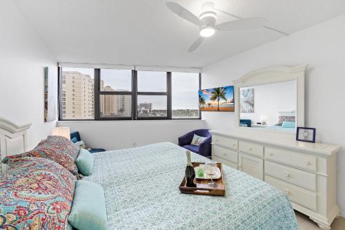 a bedroom with a bed and a dresser and windows at Beachfront condo with pool, tennis and fitness center in Marco Island