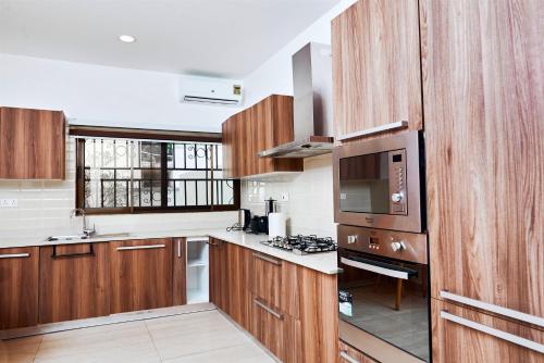 a large kitchen with wooden cabinets and a microwave at ADA - Granite Court in Accra