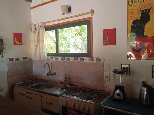 cocina con fogones, fregadero y ventana en Cabaña La Federica, en La Paloma
