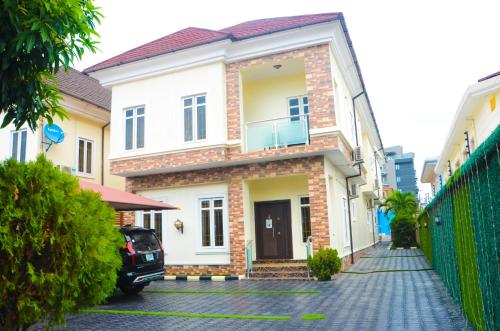 a white house with a car parked in front of it at J Gibson suite in Lekki
