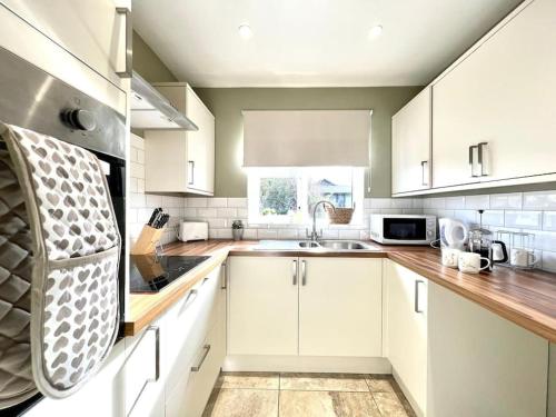 a kitchen with white cabinets and a sink at Stylish, Country, Self-Contained Annexe near Cambridge in Colne